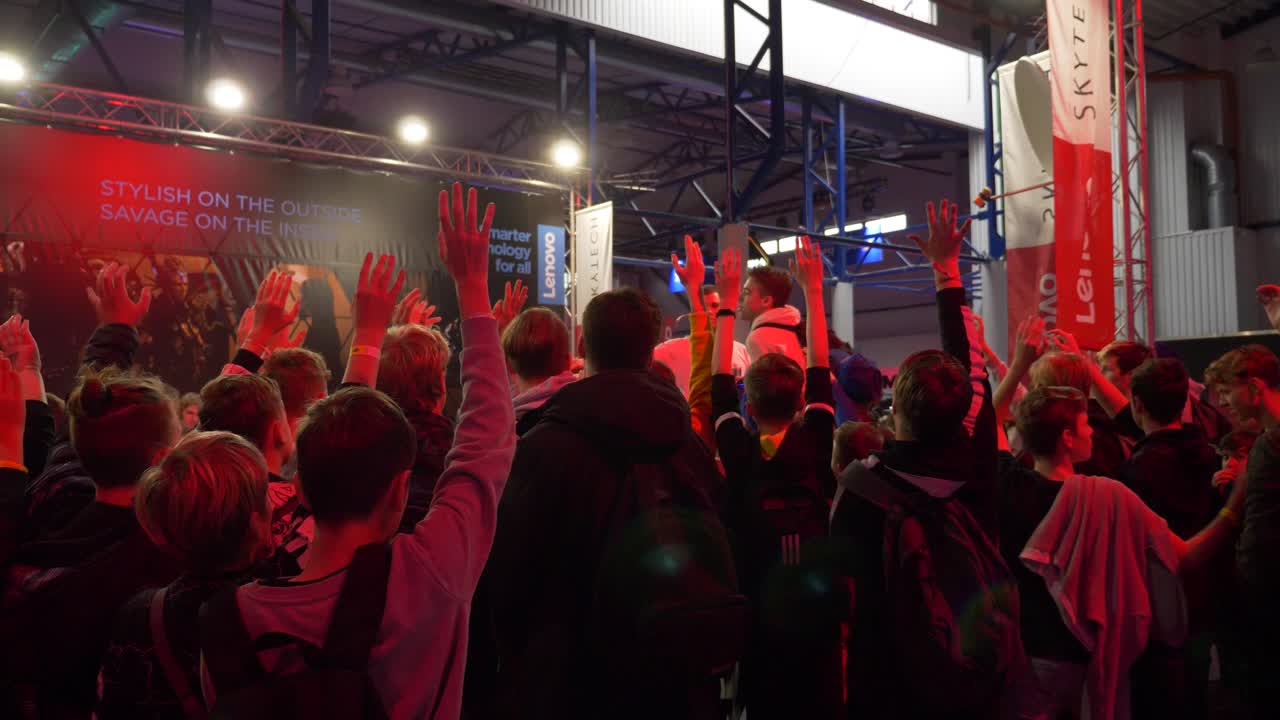 View from the back of the crowd of teenages, who tries to get to the stage to play new video game. E-sports festival.