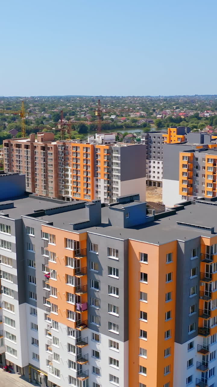 New residential complex with high-rise buildings. Modern multi-storey buildings with colorful walls. Construction site of new residential area at sunlight. Vertical video