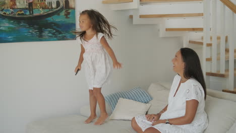 happy mother and daughter jumping on couch