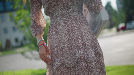 dama en vestido vintage marrón se encuentra con gracia con la mano en la cadera, posando contra el fondo de vegetación exuberante y la luz del sol, su traje complementa la belleza de la naturaleza mientras disfruta al aire libre en zapatillas de deporte casuales