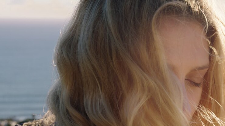 ritratto di una donna felice che ride divertendosi in vacanza d'estate godendosi il mare al tramonto con i capelli soffiati dal vento