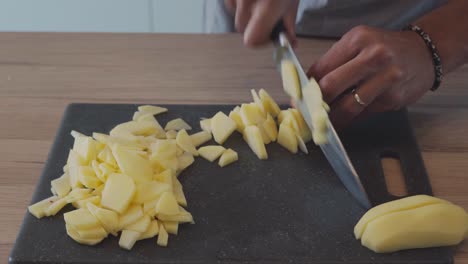 Chef-Profesional-Cortando-Patatas-Finamente-En-Una-Tabla-De-Cortar-En-Casa,-Cerrado