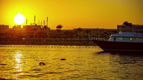 Un-Lapso-De-Tiempo-De-Atardecer-Dorado-Sobre-Hurdhada,-Egipto-Con-Un-Barco-Anclado-En-Primer-Plano