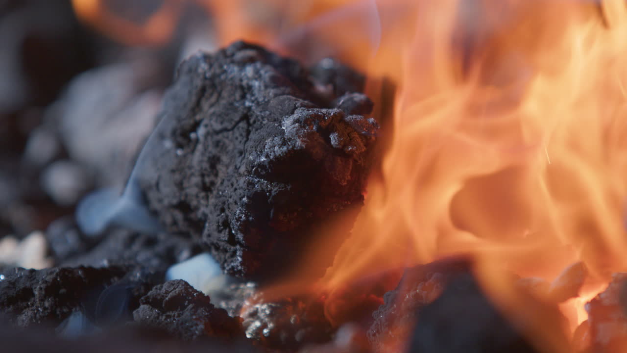 Black coals and hot burning furnace flames of blacksmith's forge, close-up view