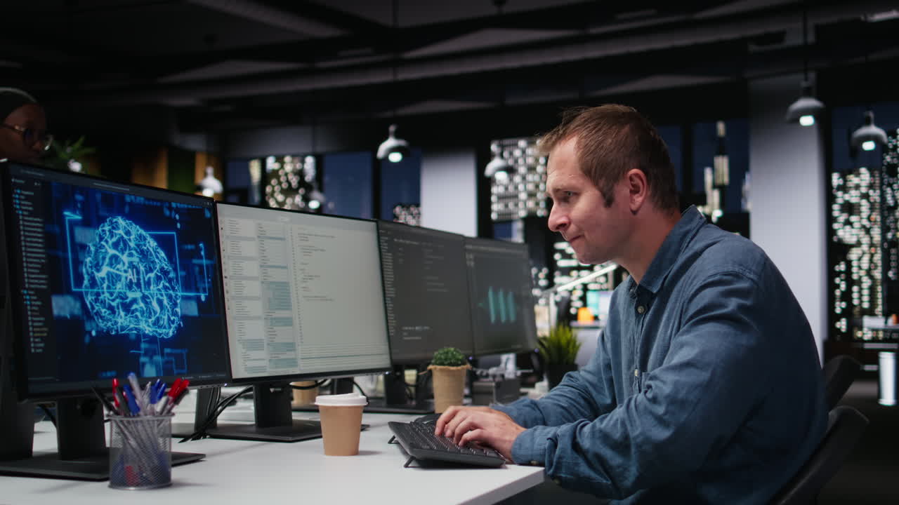 Male Programmer Working on Multiple Computer Screens in Modern Office