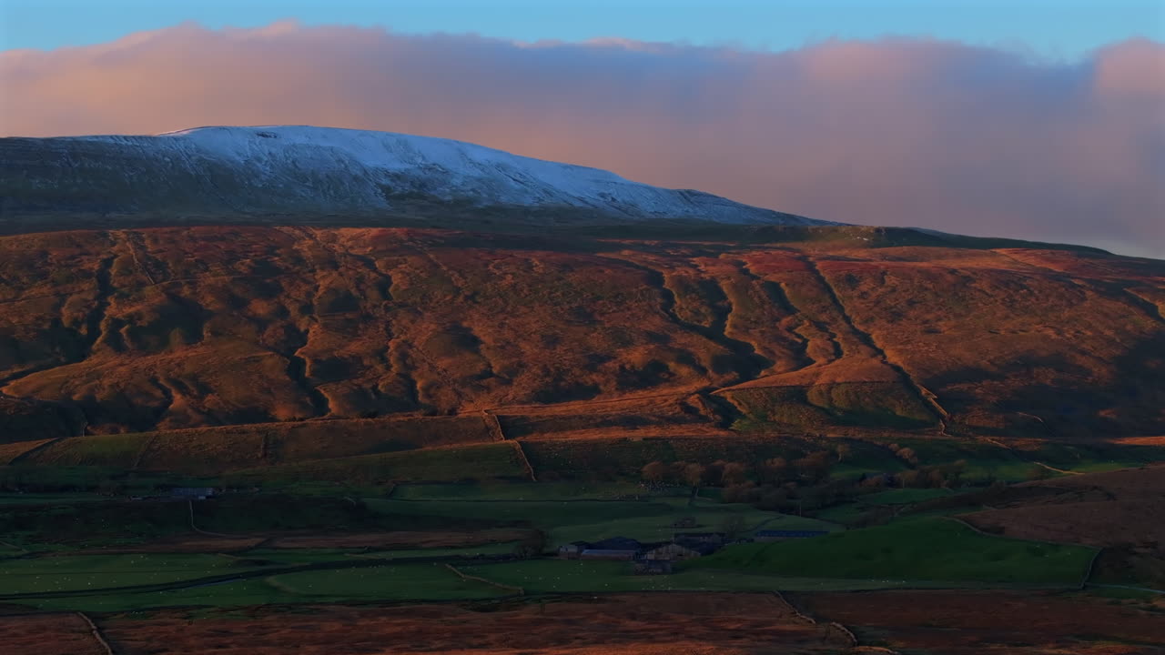tomada aérea de drones de la nieve cubierta por whernside al atardecer de la hora dorada en yorkshire dales, reino unido