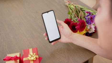 Hombre-Birracial-Con-Regalos-Teniendo-Videollamada-En-Un-Teléfono-Inteligente-Con-Espacio-Para-Copiar-En-La-Pantalla,-Cámara-Lenta