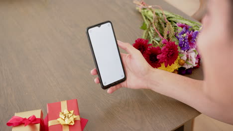 hombre biracial con regalos haciendo una llamada de video en el teléfono inteligente con espacio de copia en la pantalla, cámara lenta