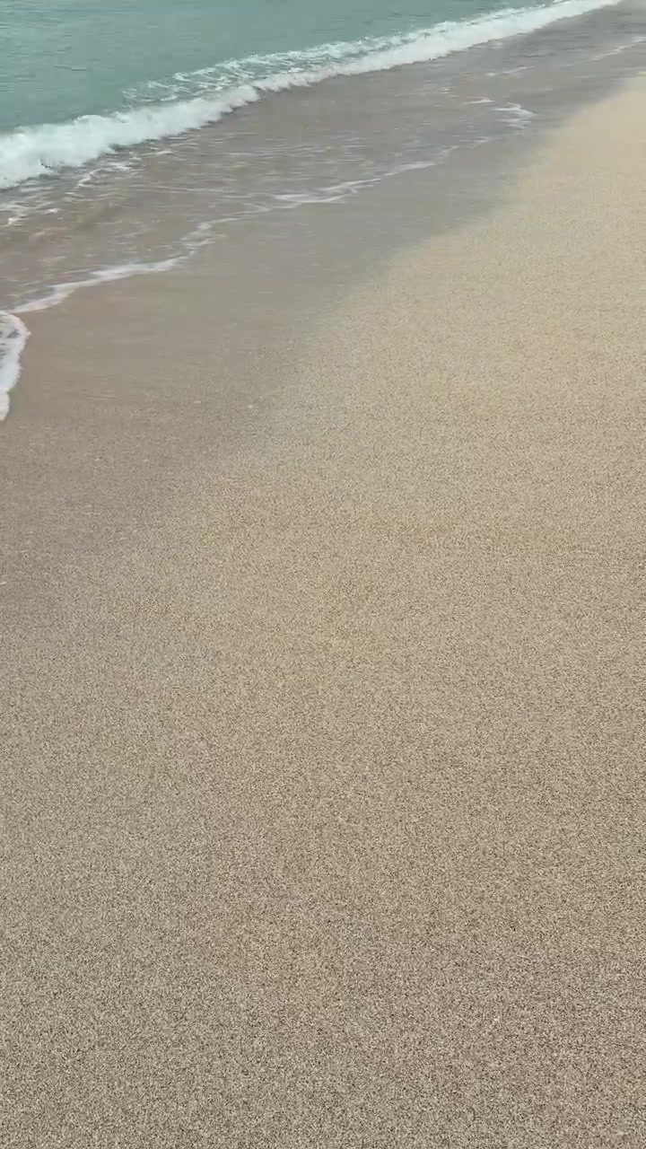 Blide havbølger, der skyller op på en sandstrand