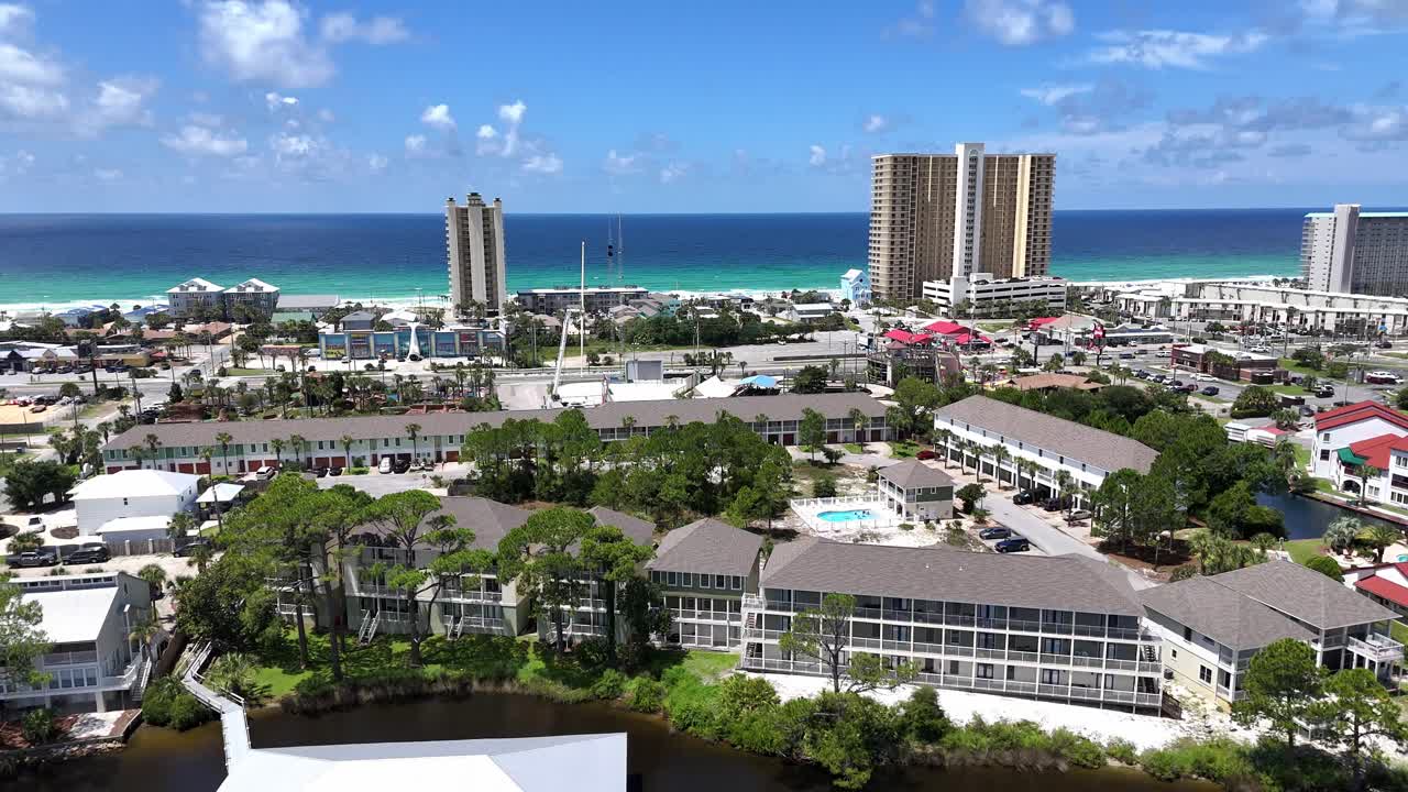 Backwards panoramic drone movement over the tourist resort area with apartments next to beauty emerald ocean bay, Panama City Beach, Florida, USA