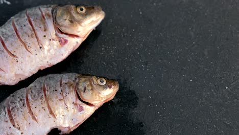 carp in spices on a black table close-up. top view.