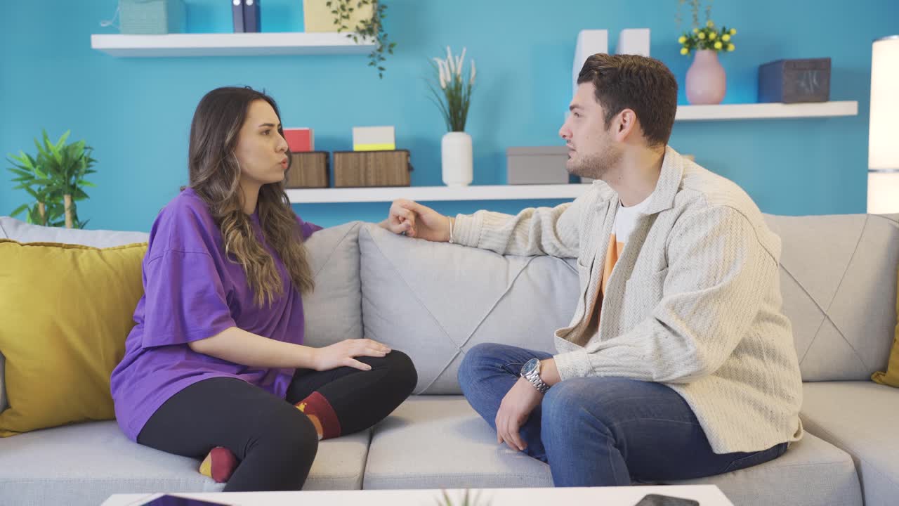 amantes felices sentados en el sofá en casa charlando, sonriendo.