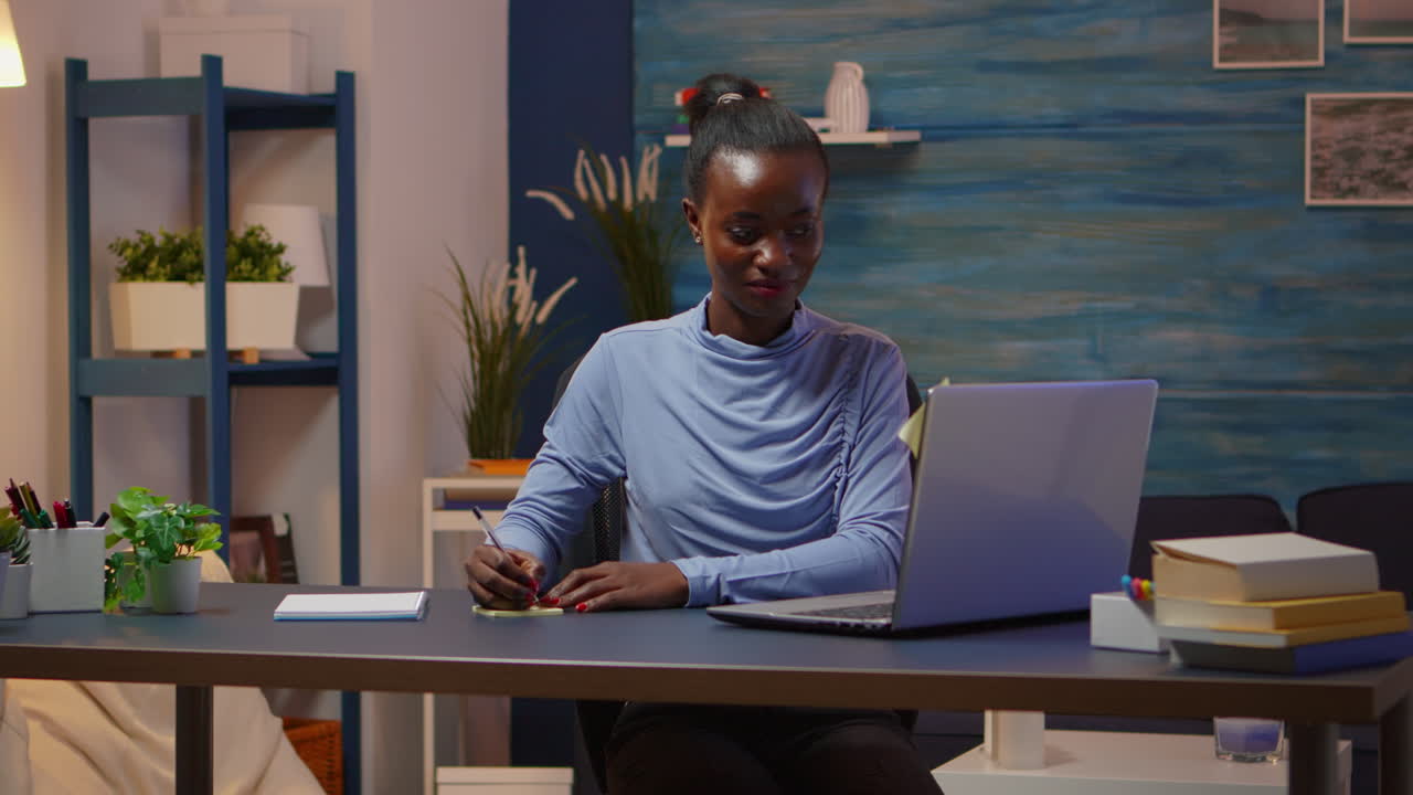 African smiling freelancer typing on computer and writing to do list