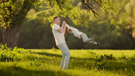 Loving-father-smiles-walking-with-the-child-sitting-on-the-neck-at-sunset-on-a-meadow-in-summer-in-slow-motion.