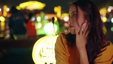 Close-up-of-pretty-Vietnamese-woman-on-boat-with-lantern-looking-at-night-river-scene,-Hoi-An,-Vietnam