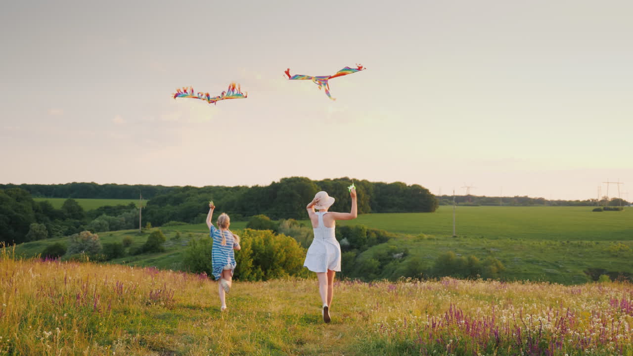 mujer con una niña corriendo con una cometa de aire feliz mamá con hija concepto vista trasera 4k cámara lenta