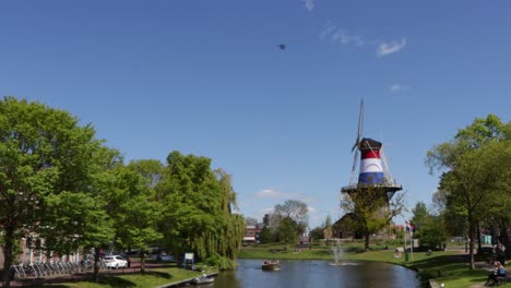 view of canal and historical windmill wrapped in dutch flag on a sunny day