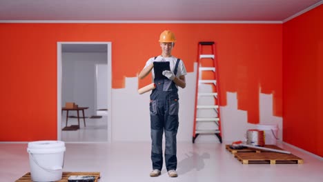 full body of asian man painter wearing safety helmet taking note on a tablet while standing with painting wall in room