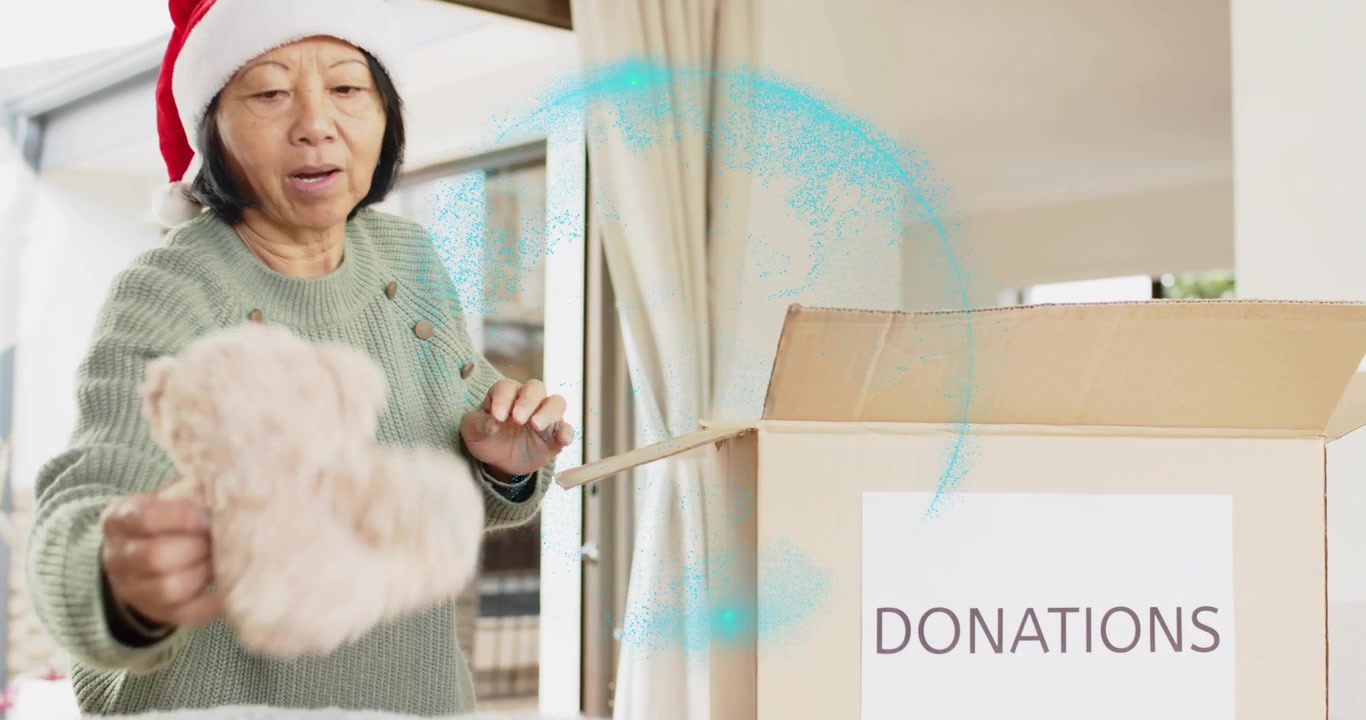 Senior woman in Santa hat reaching for sweater, donating in charity box with charity icons floating