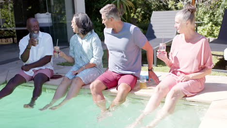 group of diverse seniors relaxing by pool, enjoying drinks and conversation in garden