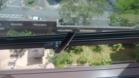 Human hand gripping a window frame with an outdoor urban view