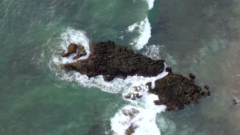 Aerial-of-waves-crashing-on-rocks-in-the-ocean-near-the-shore