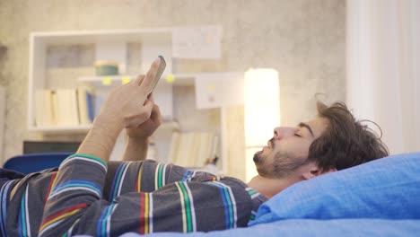 Un-Joven-Adicto-Al-Teléfono-Enviando-Mensajes-De-Texto-Por-Teléfono-En-Su-Cama.