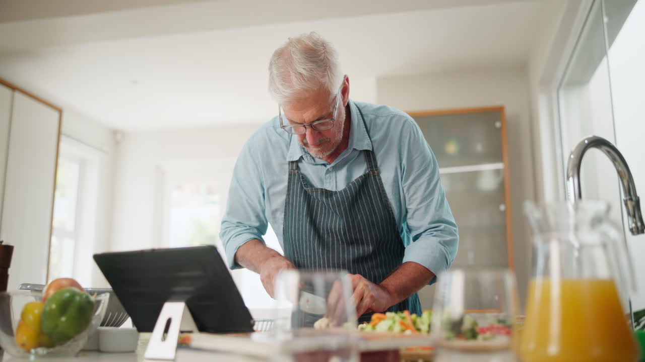 Senior man cooking with a tablet