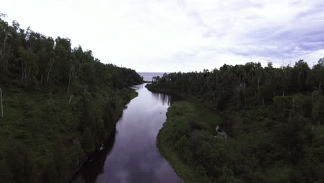 Flyover-River-Aerial-Shot-Flowing-Into-Great-Lake-with-Sky-Reflection