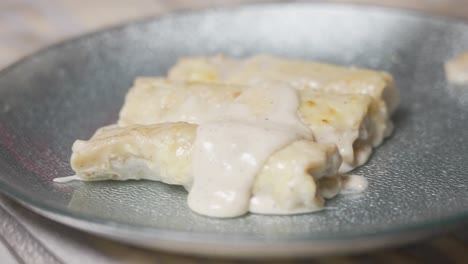 primer plano vertiendo salsa bechamel en canelones
