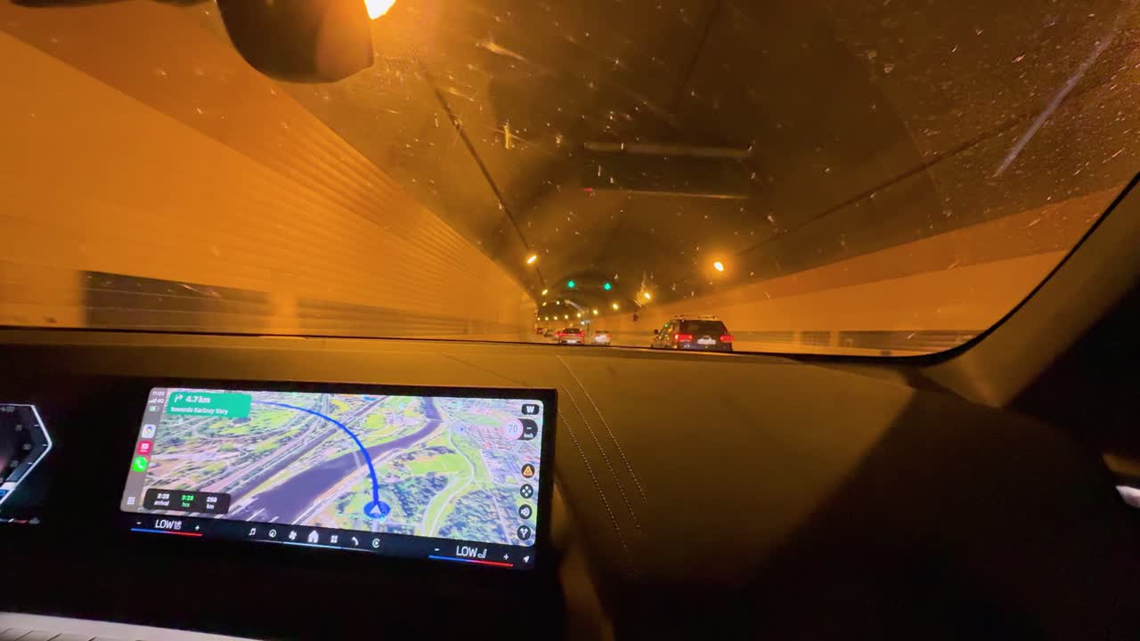 Interior car view driving through illuminated tunnel, navigation screen visible, steady camera, nighttime urban environment