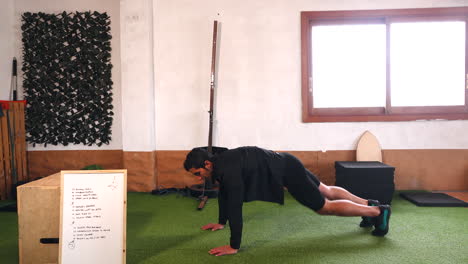 muscular trainer performs plank exercises and starts doing push-ups during online workouts