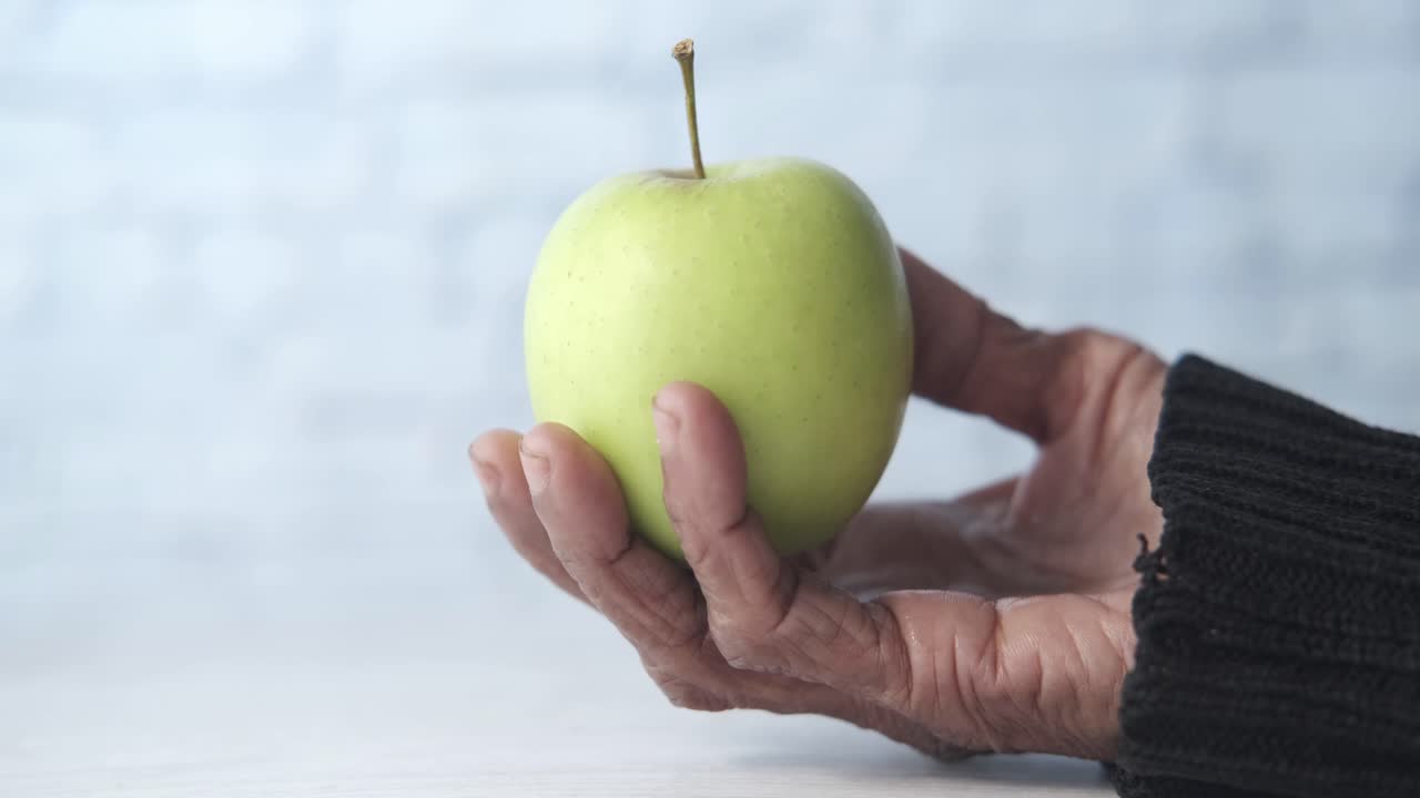 manzana verde en la mano envejecida