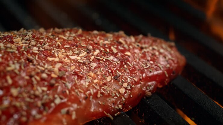 Marinated Seasoned Chicken Fillet Barbecuing On The Grill Among Fire Flames in Macro and Slow Motion