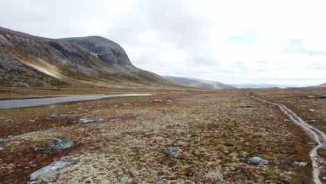 Drone-footage-of-a-person-with-a-large-backpack-hiking-through-a-Scandinavian-tundra-landscape