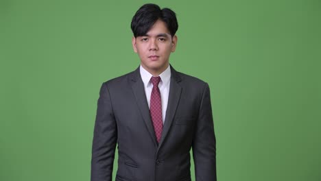 young handsome asian businessman gesturing to stop