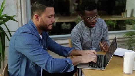 multiethnic freelancers using laptop and discussing work