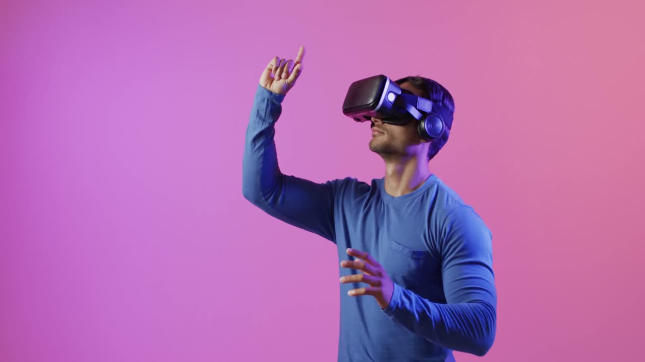 video de un hombre biracial usando auriculares vr en un fondo rosa y púrpura
