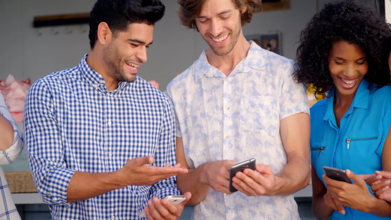 amigos interactuando mientras usan teléfonos móviles y tabletas digitales en el mostrador