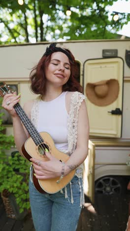 woman playing ukulele near campervan