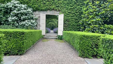 walking through a path in a garden that leads through a huge double door