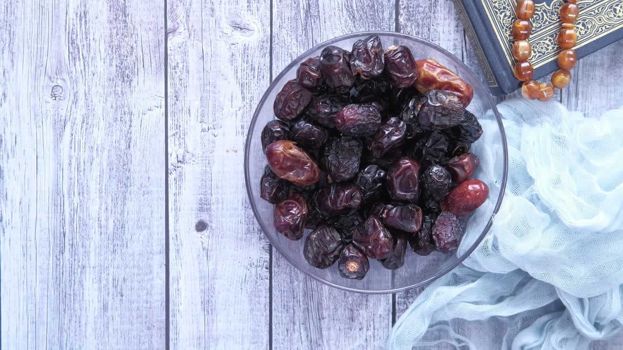 Hand reaching for dates in a bowl, Ramadan related items in the background
