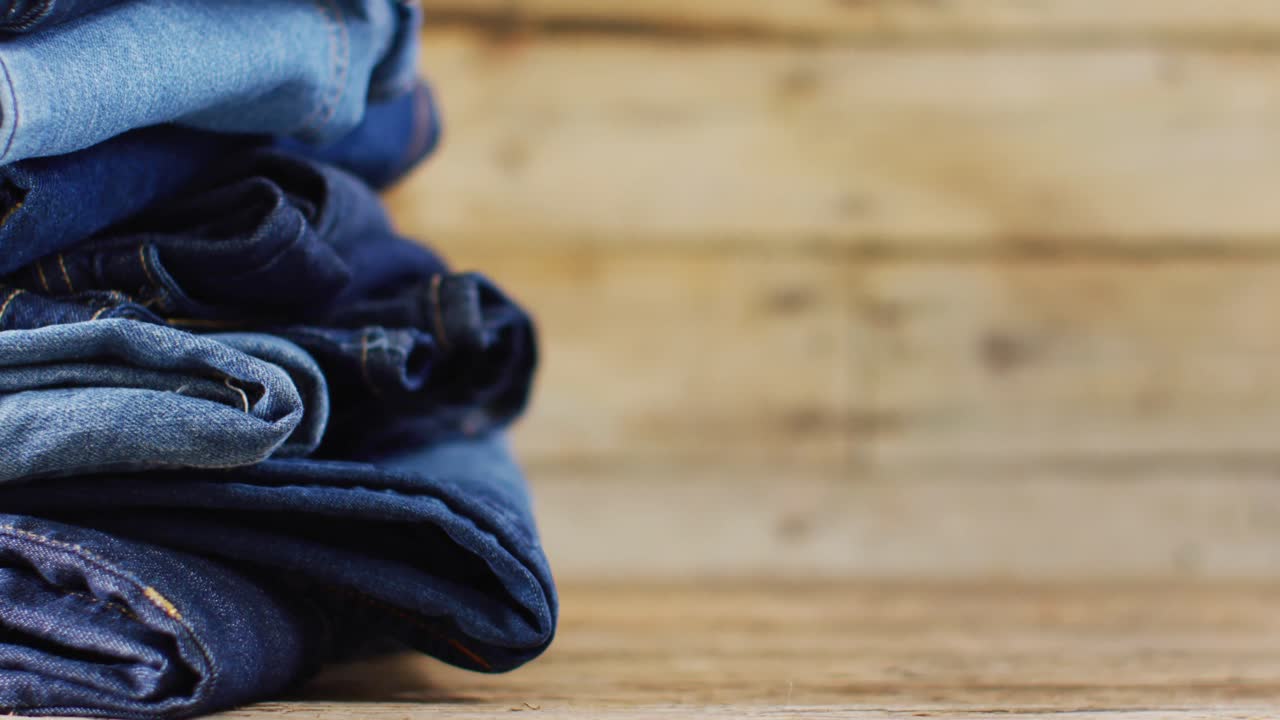 Primo piano di jeans piegati con diverse sfumature su sfondo di legno con spazio per il testo