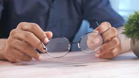 person holding round glasses on a wooden table