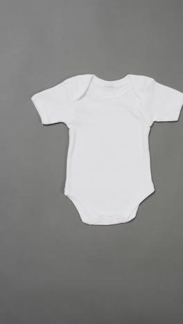vertical video of white baby grow and copy space on grey background