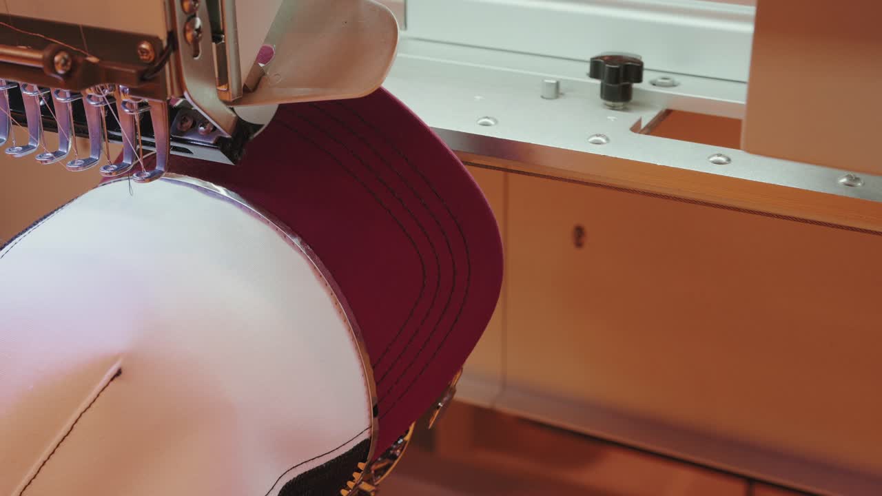 machine embroidery on maroon cap under precision stitching needle