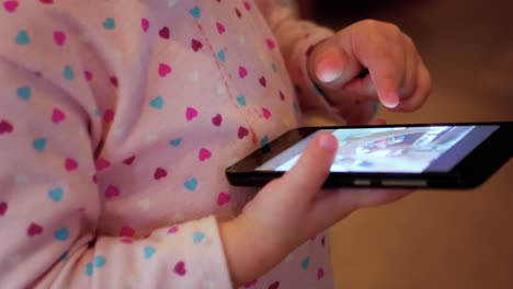 Side-view-of-a-toddler-swiping-through-pictures-on-a-cellphone