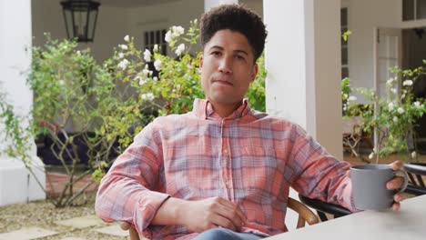 video de un hombre biracial bebiendo café en el jardín