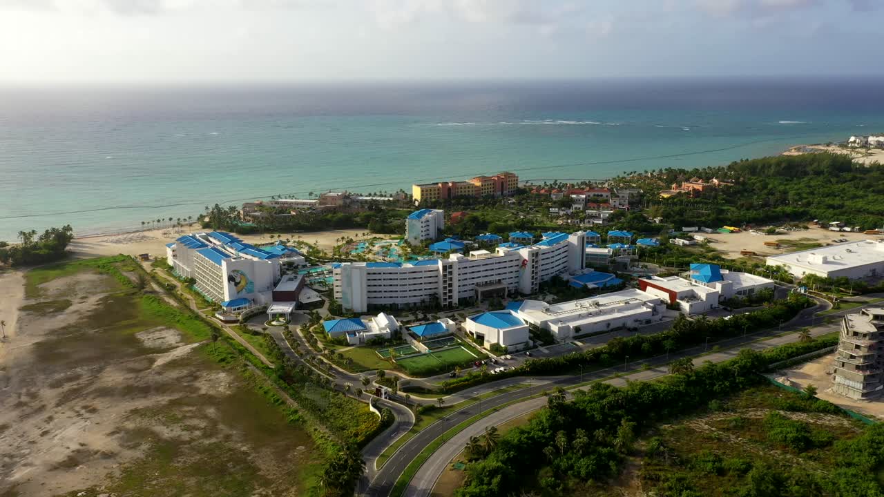 Aerial panoramic establishing of tropical coastline with green hills and sandy beach near resort in Dominican Republic