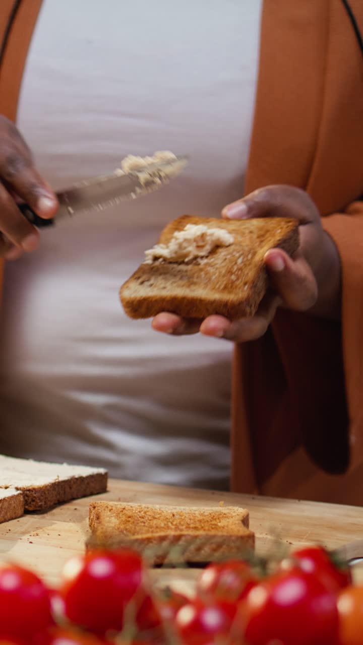 Vertical Video Close up of female chef using cream cheese spread on a bread slice